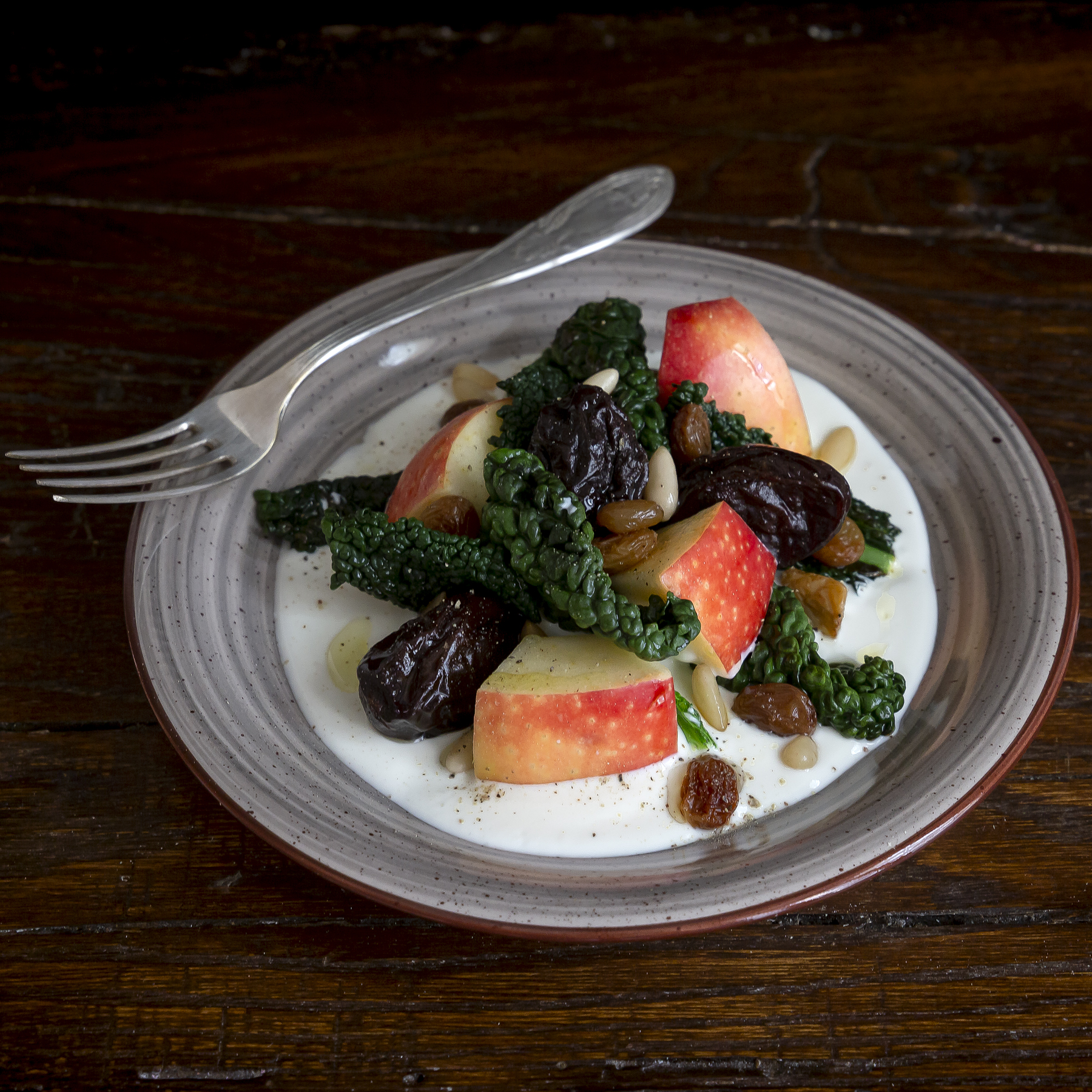 Immagine: Insalata di cavolo nero, mele, pinoli e prugne con crema calda di caprino